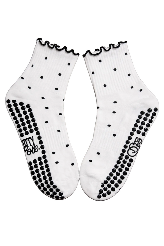 White socks with black polka dots and textured soles on a wooden surface